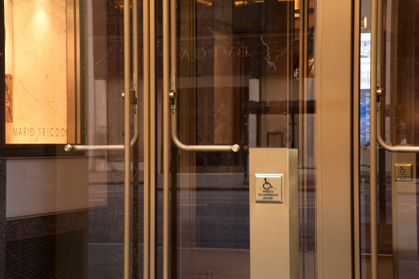 close up ada compliant glass door with handicap button pressed